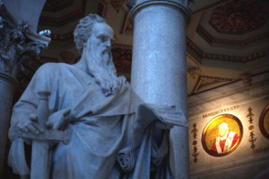 Statua di San Paolo nella Basilica di San Paolo fuori le mura con sullo sfondo il ritratto di Benedetto XVI il Papa che ha voluto l’anno Paolino
